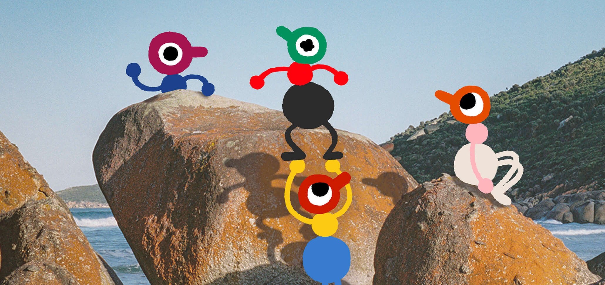 Four Big Walk characters with single large eyes gather on lichen-covered granite boulders above a beach, one pair balanced in a stack